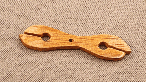 Close-up of a wooden flat shuttle used for shuttle tatting, simple lightweight design ideal for beginners.