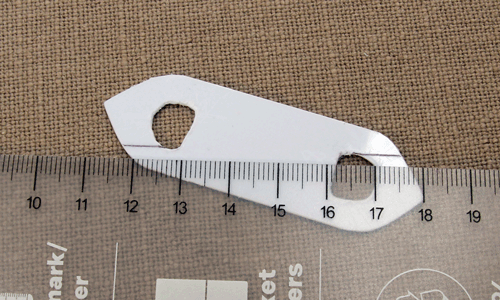 Plastic shuttle shape with ruler and marked points showing where to cut small angled notches