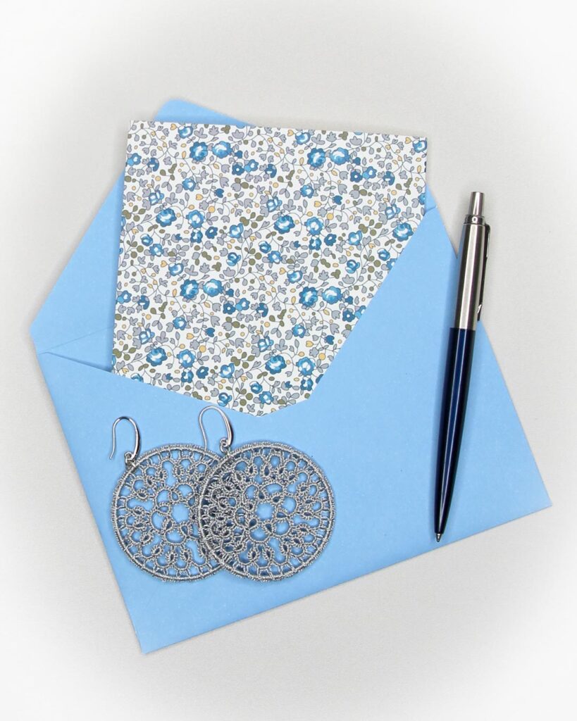Blue envelope with silver tatting lace earrings, representing contact and handmade craftsmanship.