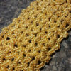 Close-up of a gold knitted tatting bracelet fragment without beads, highlighting intricate lace patterns.