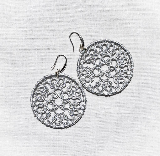 Silver rosette-shaped tatting earrings on a white background
